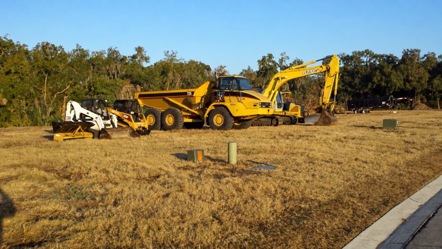 Excavator, dump truck and compact loaders on cleared ground